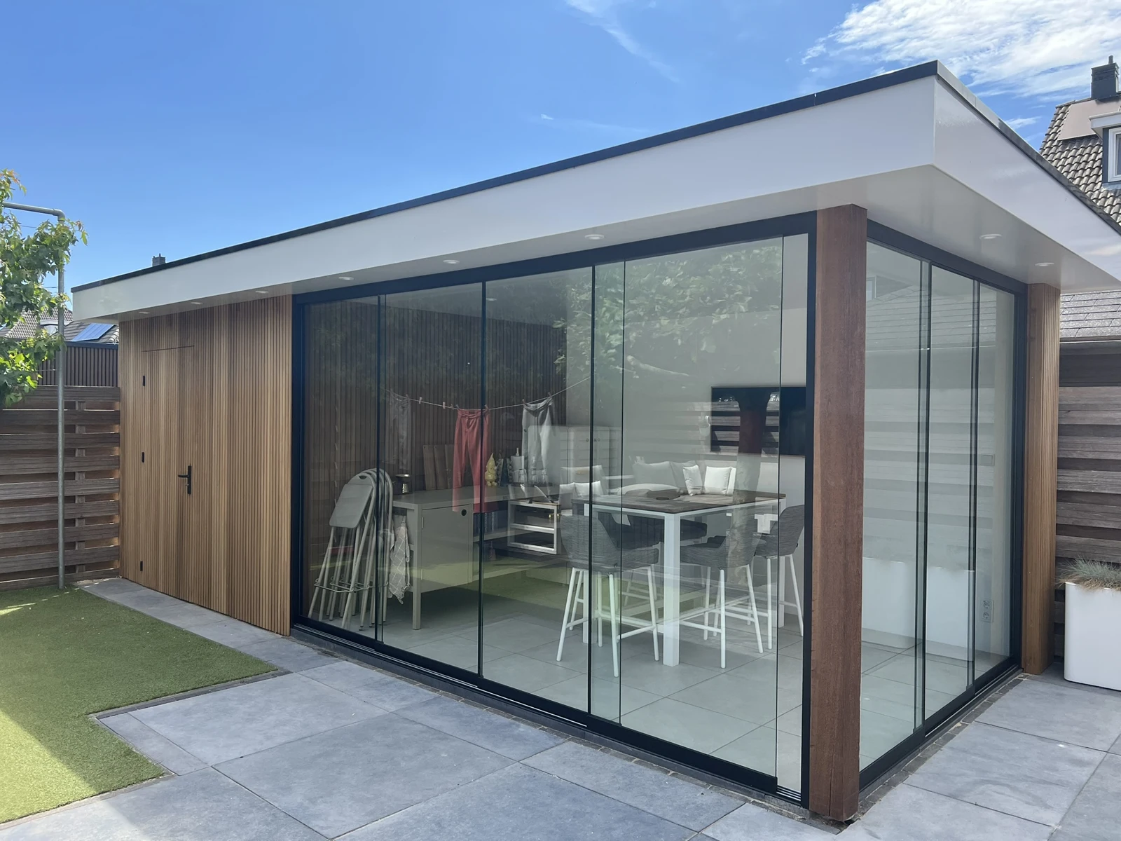 Deluxe met witte dakrand, verticale houten bekleding en glazen hoek